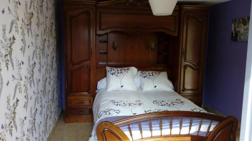 - une chambre avec un lit et une tête de lit en bois dans l'établissement Le 76, à Gamaches