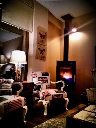 a living room with two chairs and a fireplace at Chalet Coquelicot (Co-cli-co) relax in nature in Kalavrita