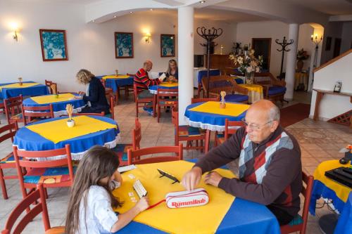 a man and a little girl sitting at tables in a restaurant at Villa Mediterran in Hévíz