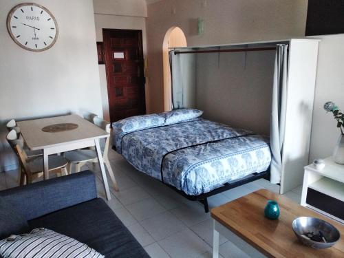 Zimmer mit 2 Betten, einem Tisch und einer Uhr in der Unterkunft Apartment Santa Eulalia Albufeira in Albufeira