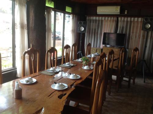 a long wooden table with chairs and a television at Happy Resort Bandung in Ban Dung