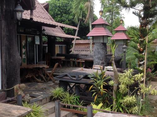a garden with a building with a table and benches at Happy Resort Bandung in Ban Dung