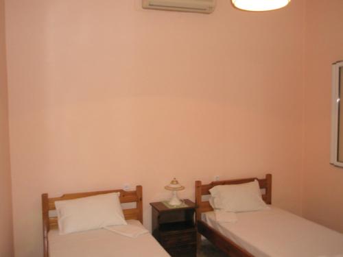 two twin beds in a room with a lamp at faliraki apartments in Benitses