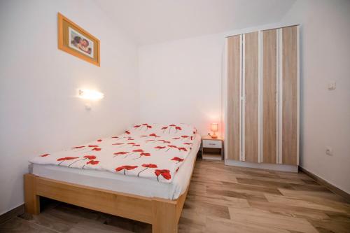 ein Schlafzimmer mit einem Bett mit roten Blumen darauf in der Unterkunft kažo in Rab