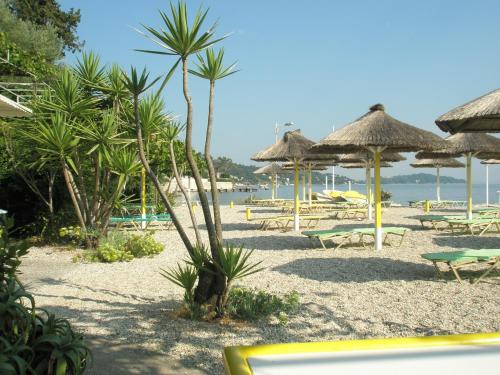 a beach with chairs and umbrellas and the ocean at faliraki apartments in Benitses
