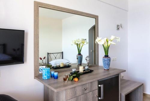 a mirror on a dresser with flowers and candles on it at Anesis Hotel in Agia Pelagia Kythira