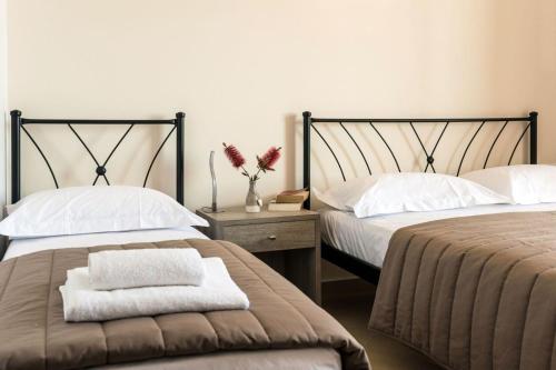 a bedroom with two beds and a vase with flowers at Anesis Hotel in Agia Pelagia Kythira