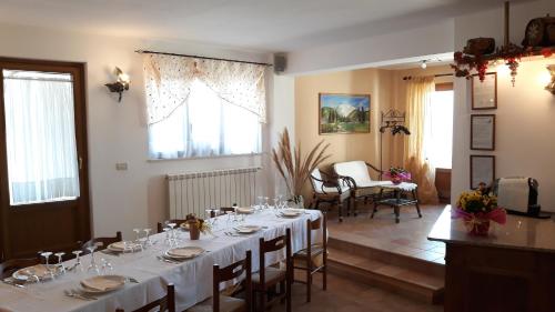 una sala da pranzo con un lungo tavolo con tovaglia bianca di Agriturismo Persichitti a Torricella Peligna