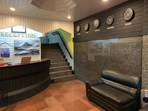 a waiting room with a leather chair and a staircase at JC Woodville Manor in Kodaikānāl