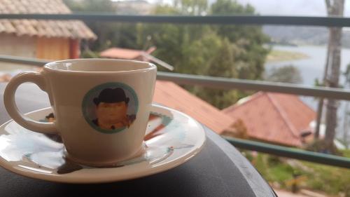 a coffee cup sitting on a plate on a balcony at Cabañas Yukatan Lago de Tota in Tota