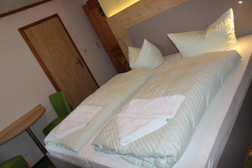 a bed with white sheets and white pillows on it at Landhotel Gasthof Zwota in Klingenthal