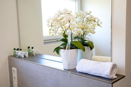 a bathroom counter with a vase with white flowers on it at sevenDays Hotel and Boardinghouse Kirchheim in Kirchheim