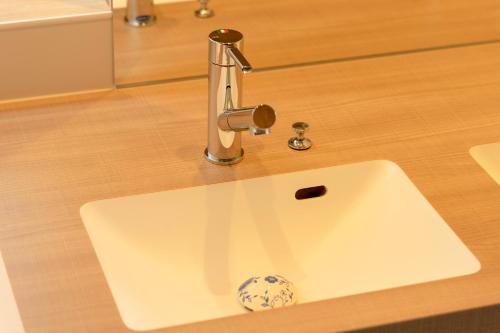 a bathroom sink with a faucet on a counter at BEACH AND FIELD INN in Sapporo