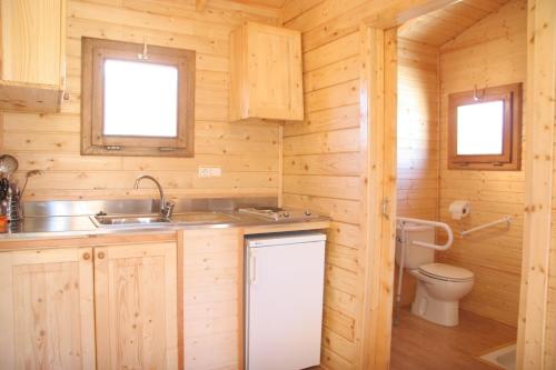 a kitchen with a sink and a toilet in a log cabin at Camping Cañones de Guara y Formiga in Panzano