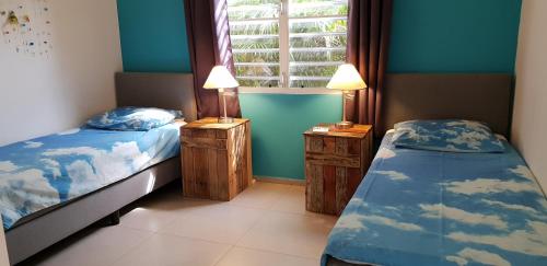 two beds in a room with blue walls and a window at Appartement Barracuda in Kralendijk