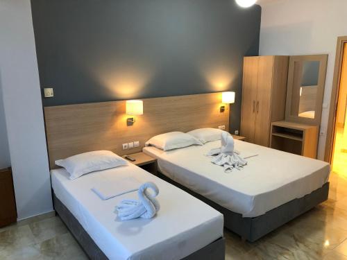 two beds in a hotel room with towels on them at Thalassa view in Áyioi Apóstoloi