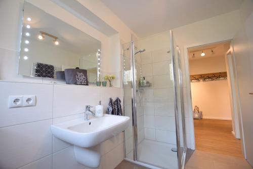 a white bathroom with a sink and a shower at Ferienwohnung Familie Anker - toll für Groß und Klein! in Hohwacht