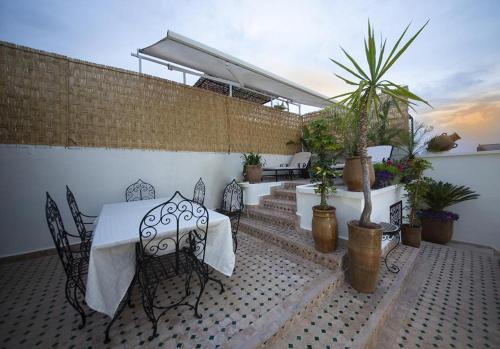 a patio with a table and chairs and potted plants at Riad Maison Belbaraka in Marrakesh