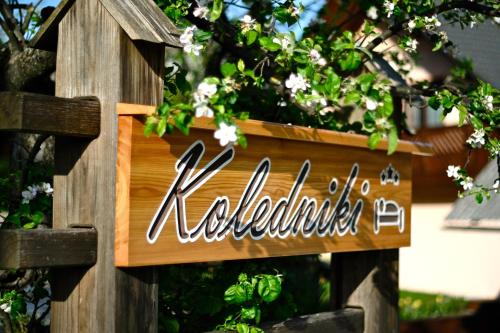 a wooden sign on a wooden fence with flowers at Apartments Koledniki in Bled