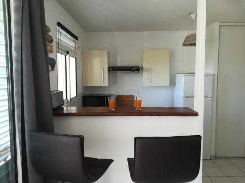 a kitchen with two black chairs and a counter at résidence les ramiers in Les Trois-Îlets