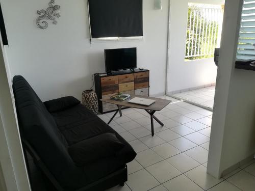 uma sala de estar com um sofá, uma televisão e uma mesa em résidence les ramiers em Les Trois-Îlets