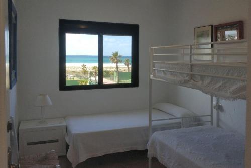 サアラ・デ・ロス・アトゥネスにあるCasa En Primera Linea De Playaのベッドルーム1室(二段ベッド2台、窓付)が備わります。