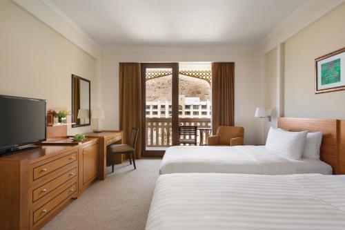 a hotel room with two beds and a television at Shangri-La Barr Al Jissah, Muscat in Muscat