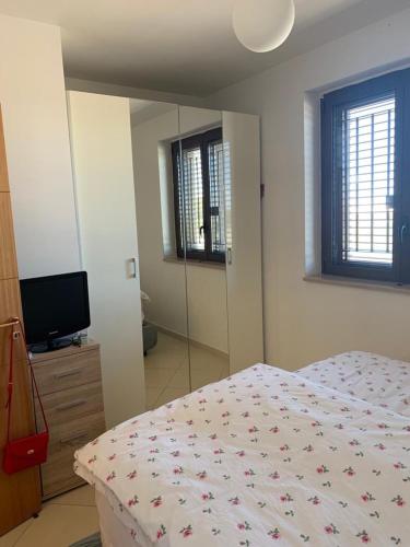 una camera con letto, TV e specchio di Salento deluxe(villetta a schiera) a Santa Maria al Bagno