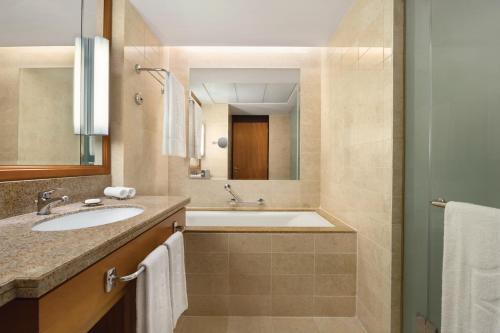 a bathroom with a tub and a sink and a mirror at Shangri-La Barr Al Jissah, Muscat in Muscat