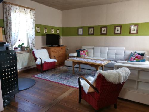 uma sala de estar com um sofá, uma mesa e cadeiras em Ferienhaus vom Bahratal em Hausen