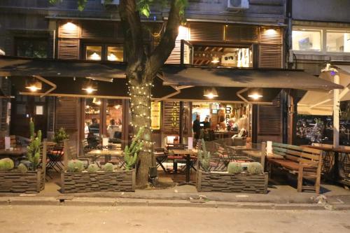 restauracja ze stołami i krzesłami oraz drzewem w obiekcie Atelier 22 w Belgradzie