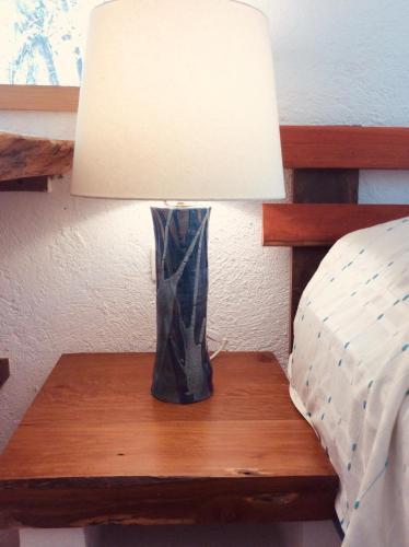 a lamp on a wooden table next to a bed at Bungalow Bé La Kin in Cozumel