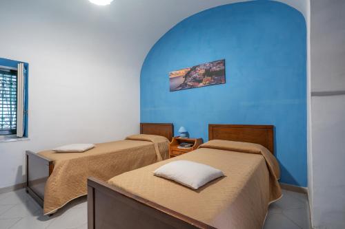 Cette chambre comprend 3 lits et un mur bleu. dans l'établissement Il Nespolo, à Vico Equense
