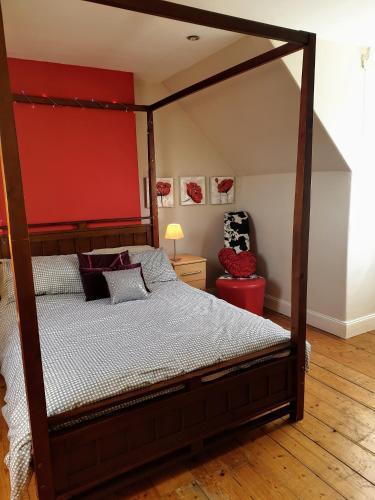 a bedroom with a canopy bed and a red wall at The Herring Queen in Eyemouth