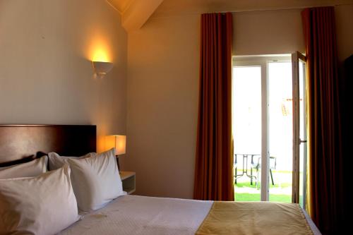 a hotel room with a bed and a sliding glass door at Guest House - Duna Parque Group in Vila Nova de Milfontes