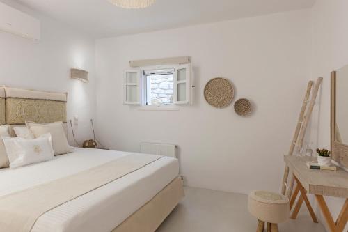 a white bedroom with a bed and a window at Amalgam Homes Paros in Ambelas