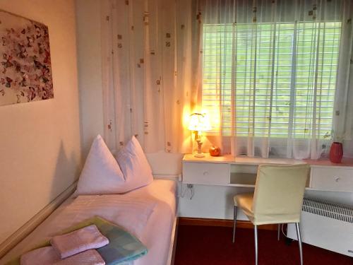 a bedroom with a bed and a desk and a window at Waldstrand Berger in Seeboden