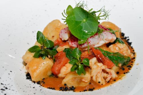 a plate of food with shrimp and greens on it at Hotel Goldene Traube in Termeno