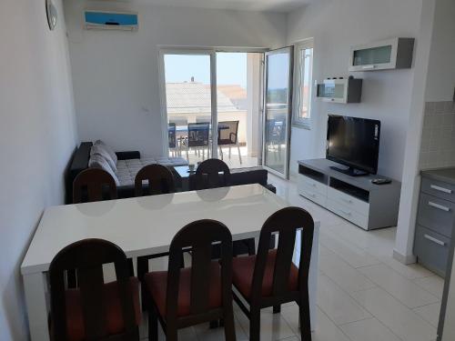 a living room with a table and chairs and a television at Apartment FERAL Novalja in Novalja