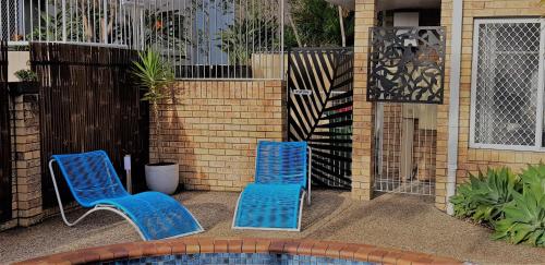 two blue chairs sitting next to a swimming pool at Limassol Motel in Gold Coast
