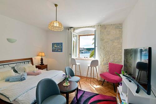 ein Schlafzimmer mit einem Bett und Stühlen sowie einem Fenster in der Unterkunft Harmony Room with a Magical SeaView in Hvar