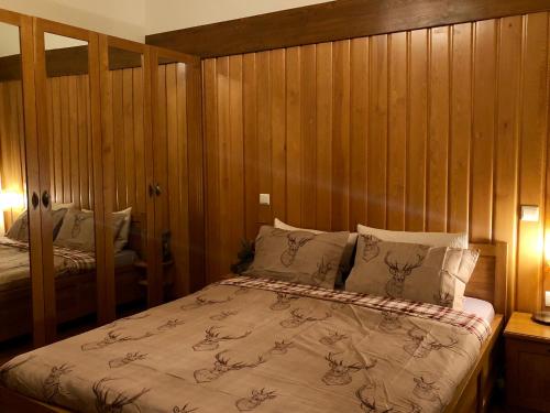 a bedroom with wooden walls and a bed with pillows at Pirin Golf and Spa Luxury Chalet in Bansko