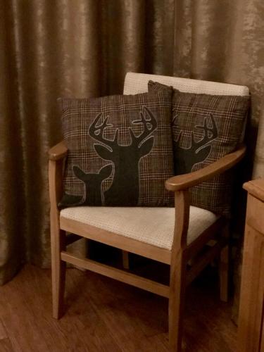 a wooden chair with two deer pillows on it at Pirin Golf and Spa Luxury Chalet in Bansko