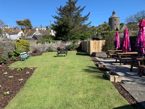 a garden with picnic tables and pink umbrellas at The Harbour House Sea front Hotel in Portpatrick