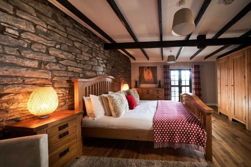 a bedroom with a bed and a stone wall at Thornhill Lodge, Historic 4 Bed, 4 Ensuite in Stirling