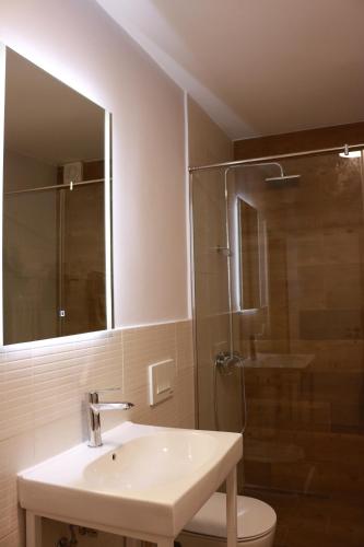 a bathroom with a sink and a shower with a mirror at Casa Abi in Tirana