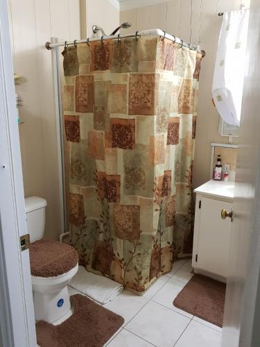 a bathroom with a shower curtain and a toilet at Tequila Sunrise Antigua in Osbourn