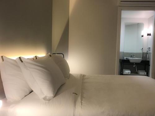 a bedroom with a bed with white pillows and a sink at Naalt Hotel Joinville in Joinville