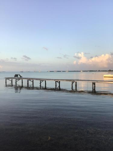 a pier on the beach with a boat in the water at Hidden Treasure Vacation Home BayBlue Suite 1 in Belize City