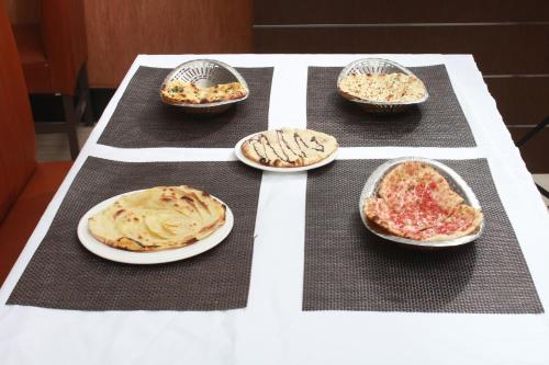a table topped with plates of different types of pizzas at Staylite Suites in Chennai